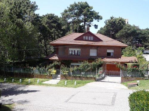 una casa con una valla frente a ella en Chalet familiar adosado Roses Rojas en Villa Gesell
