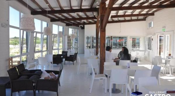 un restaurante con mesas blancas, sillas blancas y gente en Linda Bay 522 y 506 en Mar de las Pampas