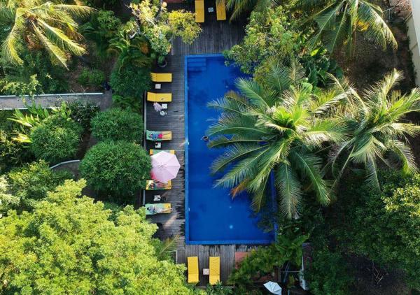 Night view of Sambor Village Hotel with lit pool, hanging lanterns, and lush greenery surrounding seating area