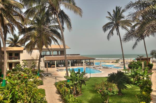 Swimming pools and lounge chairs surrounded by palm trees and gardens at Sunset Beach Hotel by the ocean