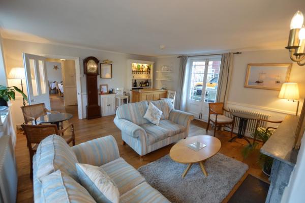 Living room with striped sofas, wooden coffee table, grandfather clock, small bar, and French doors with curtains