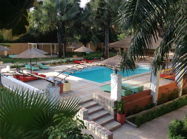 Outdoor pool area with sun loungers, thatched umbrellas, palm trees, and stone steps at Calabash Apartment-Hotel