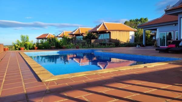 Outdoor swimming pool with clear blue water reflecting traditional style buildings under a blue sky