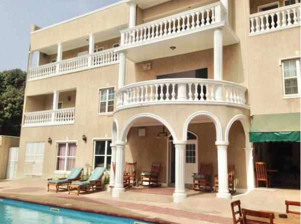 three-story villa with white columns and balconies beside a swimming pool with lounge chairs