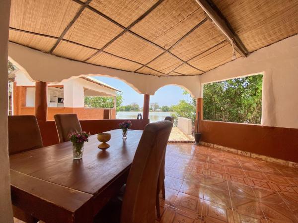 Covered outdoor dining area with wooden table, chairs, and view of river and greenery