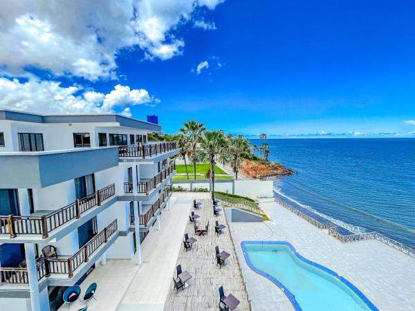 Majula Boutique Hotel with balconies overlooking a pool, palm trees, and ocean under a blue sky with clouds