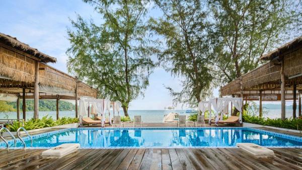 Outdoor pool with wooden deck, lounge chairs, cabanas, and sea view at Eden Beach Resort by EHM