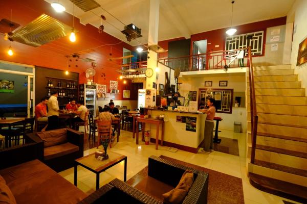 Interior view of Route 76 Guest House lobby with seating area, reception desk, and outdoor dining space