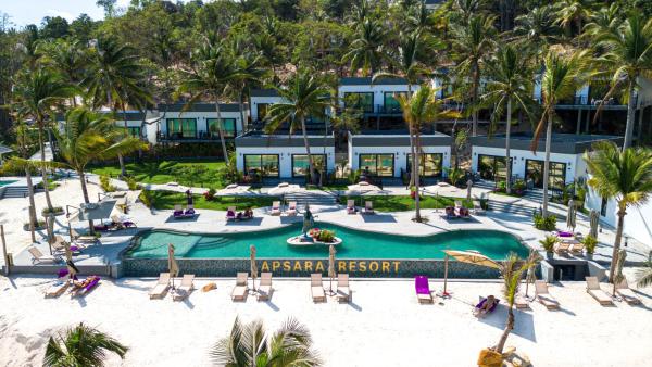 Apsara Resort Koh Rong with modern white buildings, a curved pool, palm trees, and sandy beach under daylight