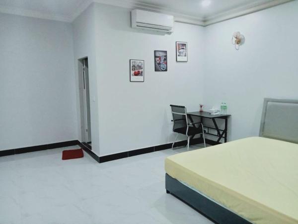 Simple bedroom with a bed, desk with chair, air conditioner, and three framed pictures on the wall