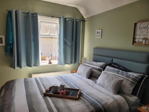 Bedroom with double bed, striped bedding, blue curtains, and soft green walls with framed pictures