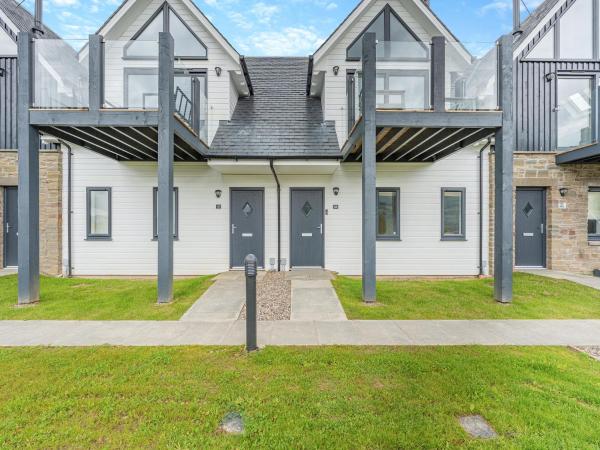 Front view of modern two-storey white and stone holiday homes with grey doors and glass balcony railings