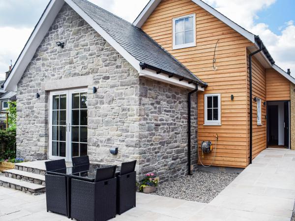 stone and wood exterior of Rubys Cottage with glass door and outdoor black wicker dining set