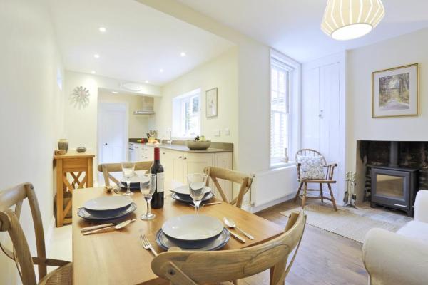dining table set for four in a bright kitchen with wooden chairs and a wood-burning stove