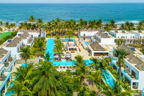 aerial view of Kalimba Beach Resort with white buildings, swimming pools, palm trees, and ocean in the background