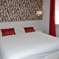 a bedroom with a white bed with two red pillows at Hôtel Restaurant LE MONARQUE, Blois