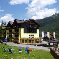 a building with chairs in the grass in front of it at Hotel Cime D'Oro, Madonna di Campiglio
