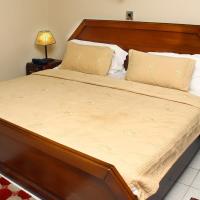 a large bed with a wooden headboard in a bedroom at Stadium Hotel, Kumasi