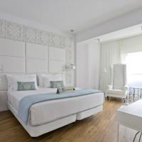a white bedroom with a large bed and a chair at Hotel Tres Reyes Pamplona