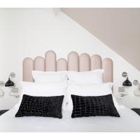 a bedroom with a white bed with black and white pillows at Hotel Restaurant Les Capucins, Belfort