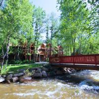 a red bridge over a river with a house at Streamside on Fall River, Estes Park