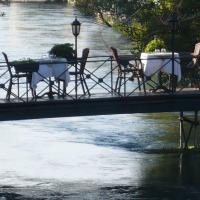 a table and chairs on a bridge over a river at Les Terrasses de David et Louisa, L'Isle-sur-la-Sorgue