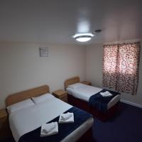 a hotel room with two beds and a window at Woodlands Lodge Ilford