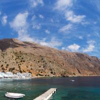 a group of boats docked in the water next to a mountain at Daskalogiannis Hotel, Loutro
