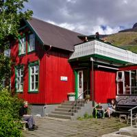 a red building with people sitting outside of it at Hafaldan HI hostel - Seydisfjordur, Seyðisfjörður