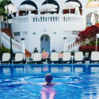 a person in a swimming pool with a cruise ship at Beverly Hills Heights - Excel Hotels & Resorts, Los Cristianos