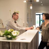 a man and a woman shaking hands at a counter at Refborg Hotel, Billund