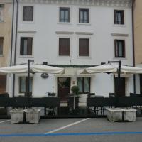 a building with tables and umbrellas in front of it at Valentino, Portogruaro