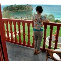 a woman standing on a balcony looking out at the ocean at Hotel Villa Itsaso, Lekeitio