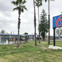 a sign in front of a building with palm trees at Motel 6-Visalia, CA