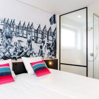 a bedroom with a large white bed with two colorful pillows at Hotel Nelson, Knokke-Heist