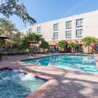 a pool in front of a hotel with tables and umbrellas at Hyatt Place Sarasota/Bradenton