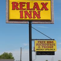 a yellow sign for a relax inn with a sign for a restaurant at Relax Inn Vinita