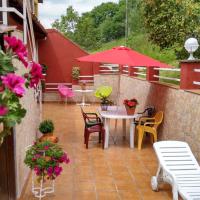 a patio with a table and chairs and pink flowers at Apartamentos Huerta Carúa I y II, Piloña
