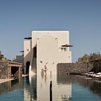 a resort with a pool and chairs and a building at Istoria, a Member of Design Hotels, Perivolos