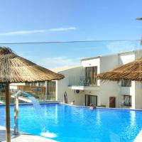 a pool with a water slide and two straw umbrellas at Porto Demo Hotel, Agios Georgios Pagon