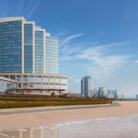 a tall building on the beach next to the ocean at Hyatt Regency Qingdao - Stone old beach - Exhibition Center