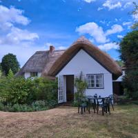 a cottage with a thatched roof with a table and chairs at Stable Cottage, Devizes