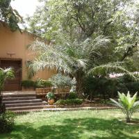 a garden with palm trees and stairs in front of a house at Hôtel Les Palmiers, Ouagadougou
