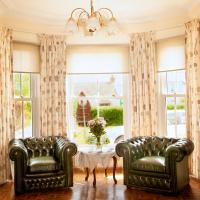 two leather chairs and a table in a room with windows at Burford Lodge Guest House, Ardglass