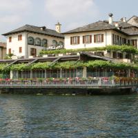 a building with flowers on the side of a river at Hotel Leon D'Oro, Orta San Giulio