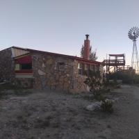 a stone building with a windmill in the background at La loma del chivo-Stone Cottage(alternative building), Marathon