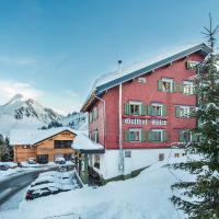 a large red building with cars parked in the snow at Adler Damüls Gasthof Hotel, Damuls