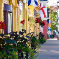a street with buildings with flowers and a flag at Rum Runner Inn, Lunenburg
