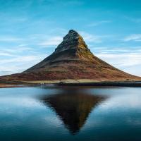 a mountain sitting next to a body of water at Kirkjufell Hotel by Snæfellsnes Peninsula West Iceland - Grundarfjordur
