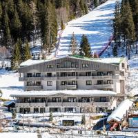 a large building in the snow in front of a mountain at Hotel Spinale, Madonna di Campiglio